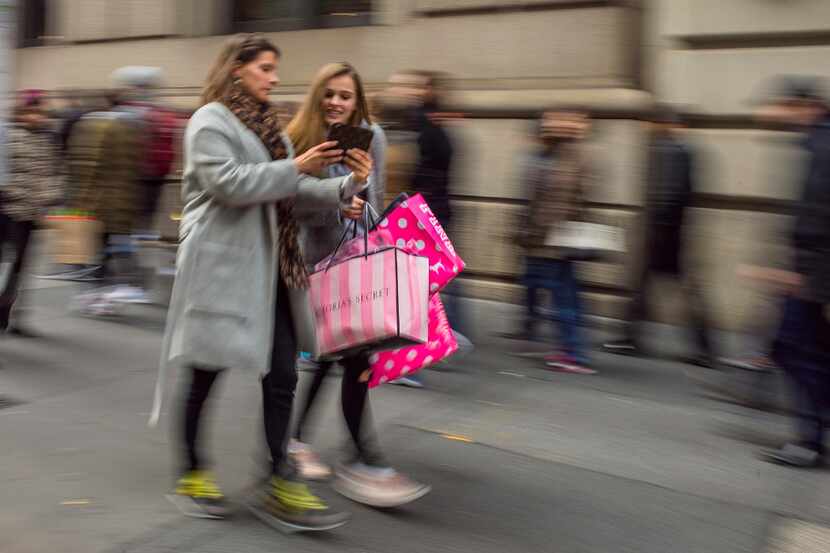 FILE - In this Friday, Nov. 25, 2016, file photo, shoppers carry their purchases as they...