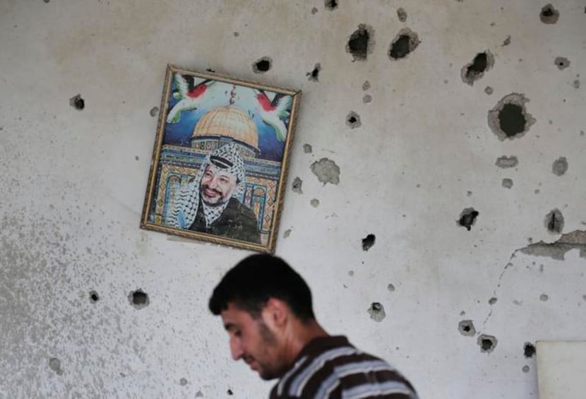 
A picture of late Palestinian leader Yasser Arafat hangs askew as a member of the...