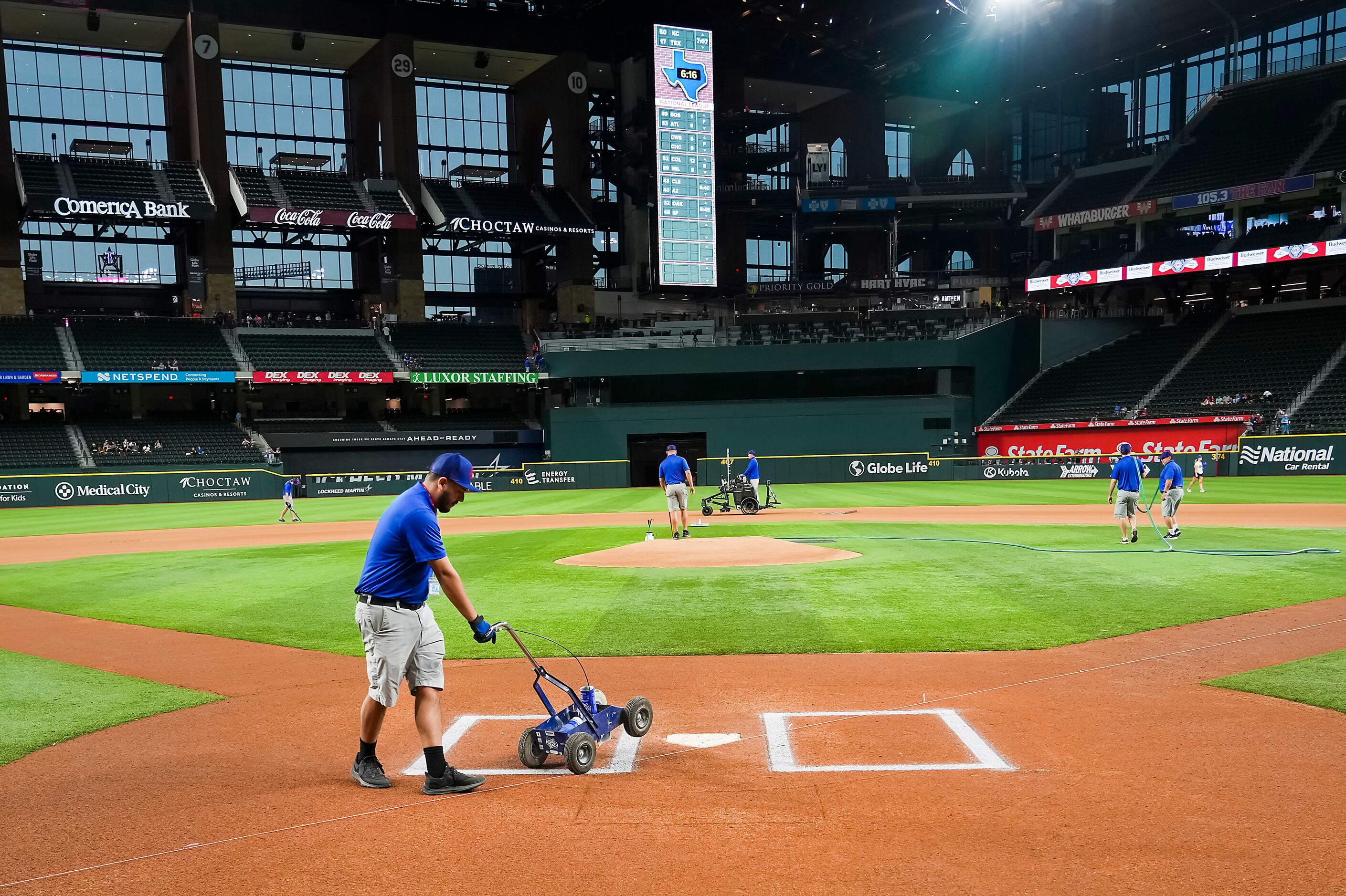 Groundskeepers prepare the field before an exhibition baseball game between the Texas...
