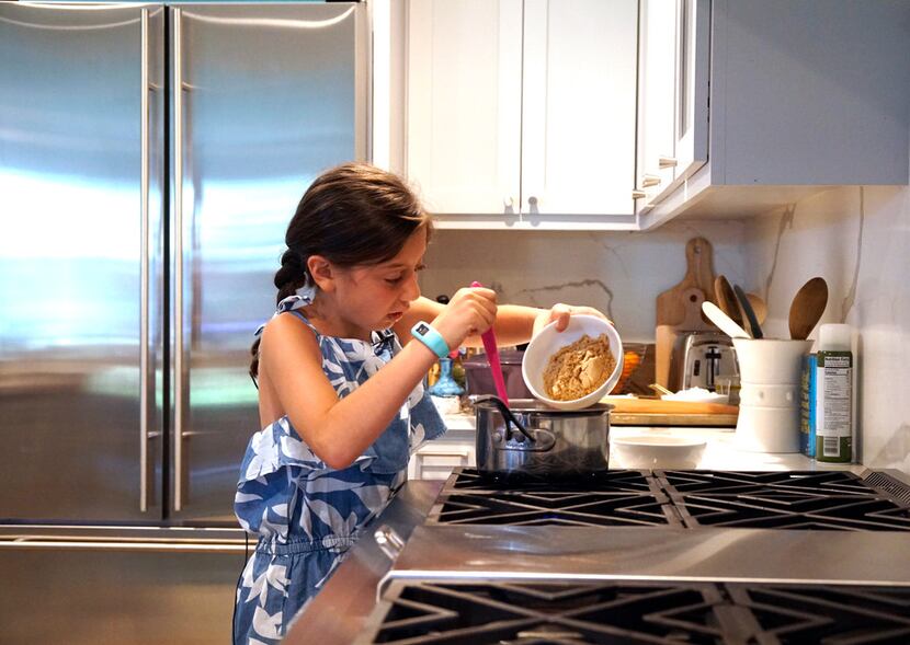 Sophie Massad (8) adds ingredients for granola bars at her home in Dallas.