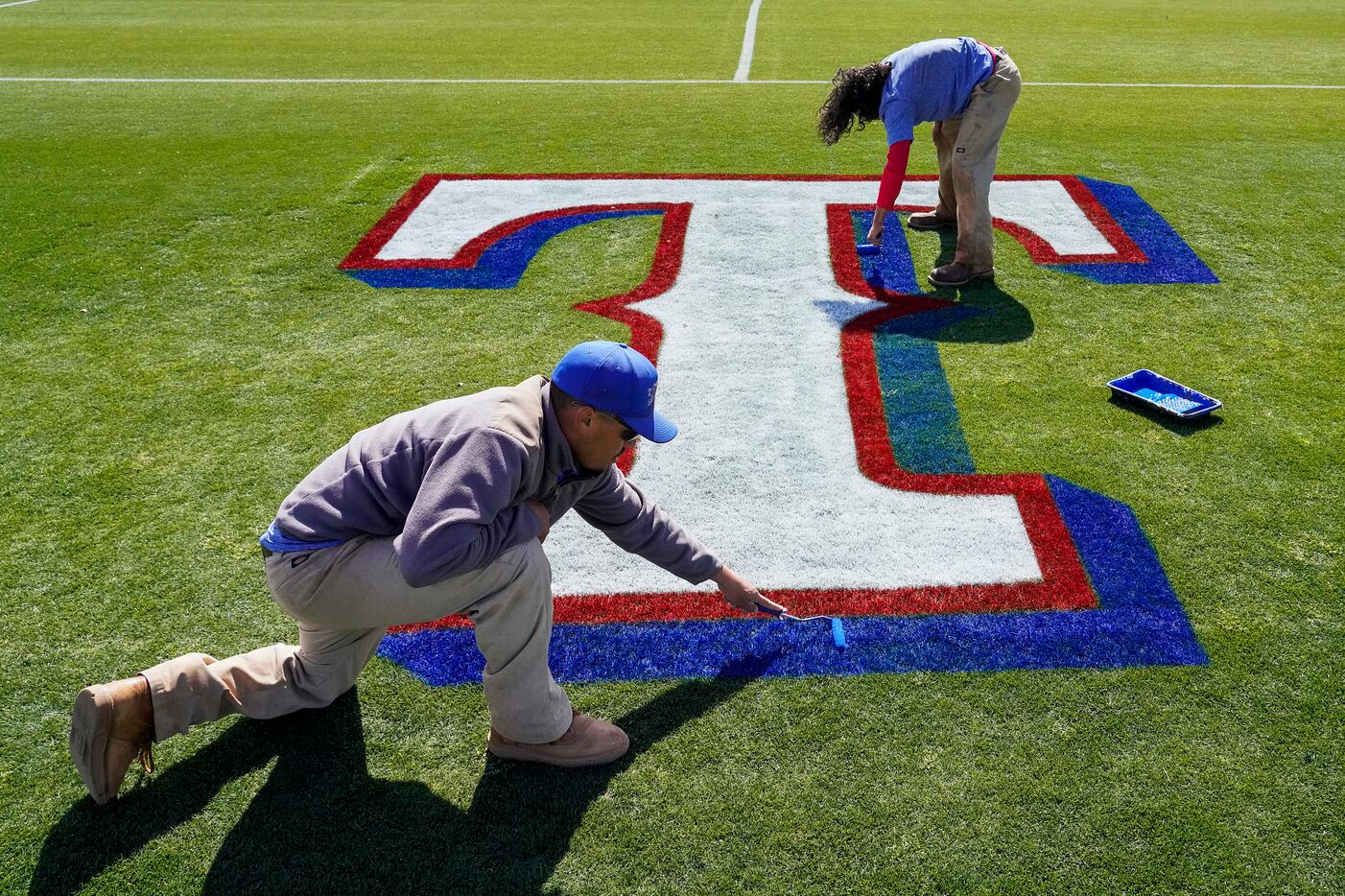 Brandon Rodriguez (left) and Anthony Encinas paint the team logo on a conditioning field...