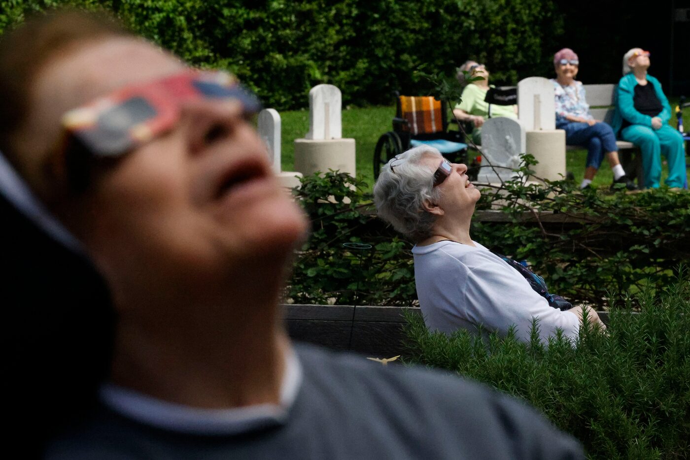 Residents of St Joseph's Residence Inc. look up from the back yard to watch the total solar...