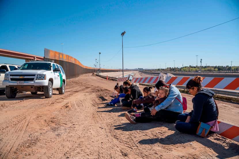 Inmigrantes de El Salvador esperan ser transportados por una camioneta de la Patrulla...