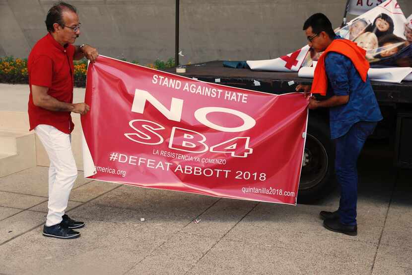 Carlos Quintanilla, left, and Francisco Salinas prepare to roll up an anti SB4 banner used...