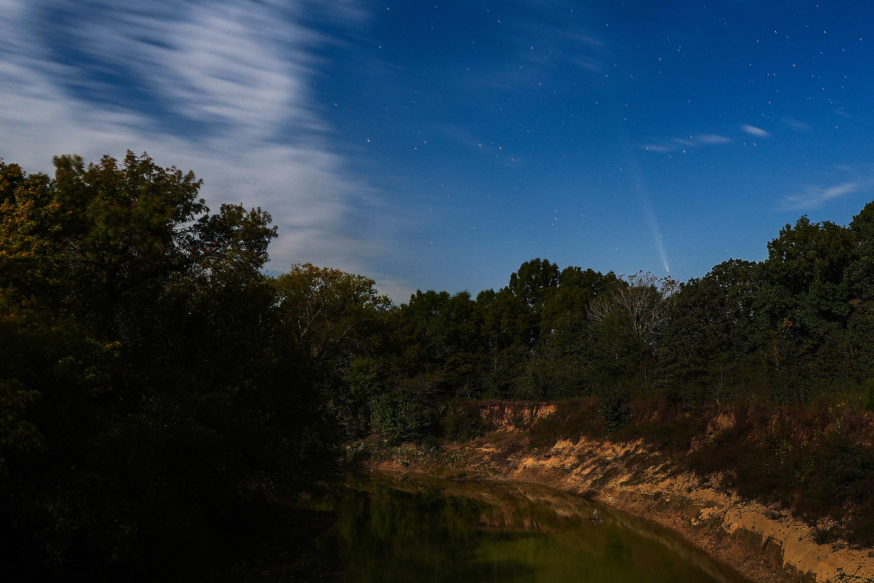 The faint streak of comet Comet A3 Tsuchinshan-ATLAS is seen over the Sulpher River, which...