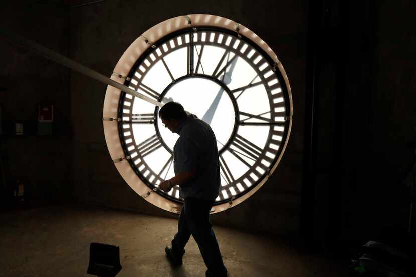Historic clock restoration specialist Chuck Roeser of Lockport, New York ducks under one of...