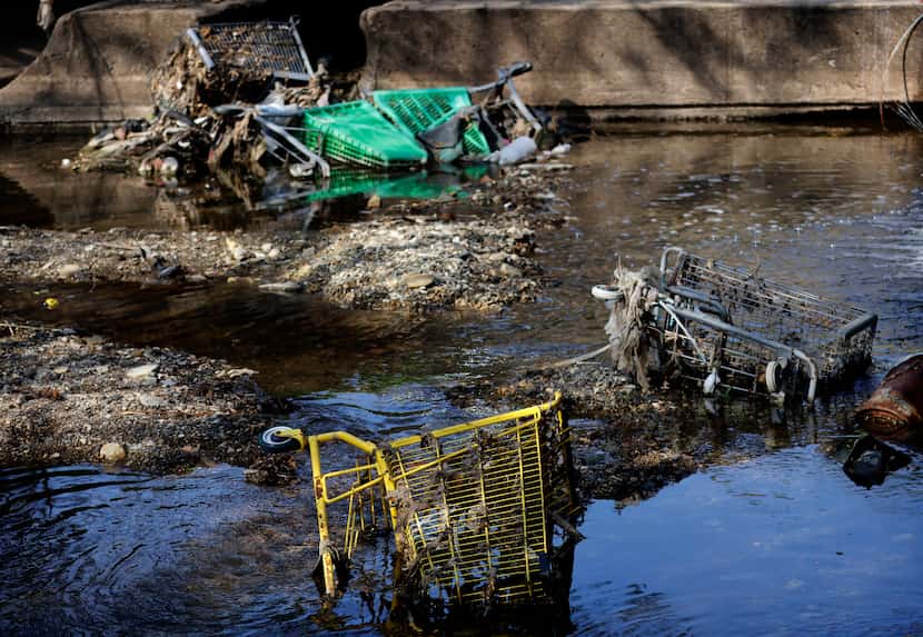 Old shopping carts are half buried in West Joe’s Creek Tuesday, part of a growing garbage...