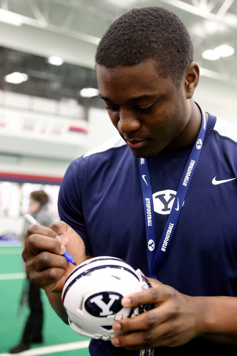 Tejan Koroma signs a miniature BYU helmet for Allen defensive coordinator Cory Cain before...