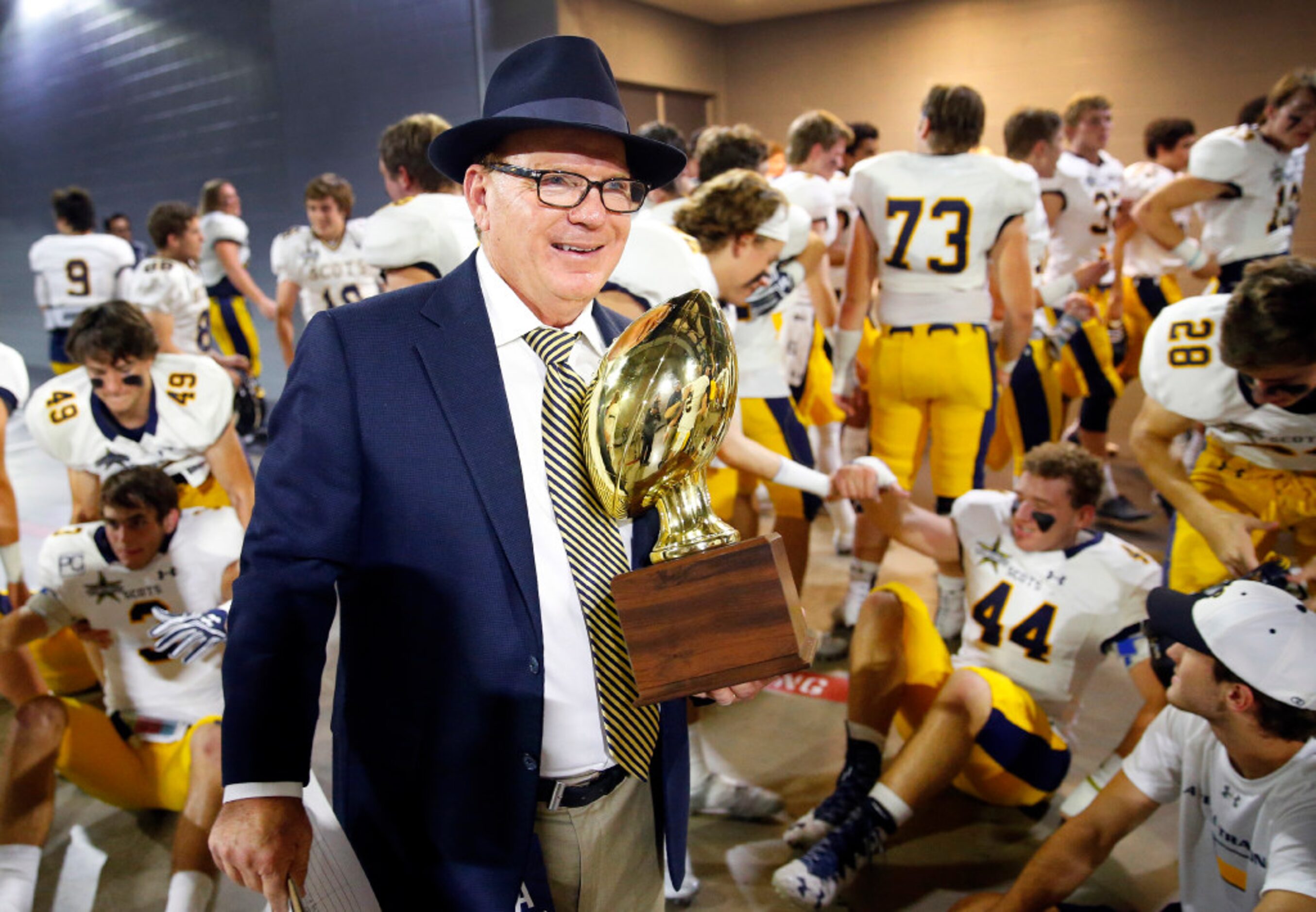 Highland Park head football coach Randy Allen carries the winning trophy after a team photo...