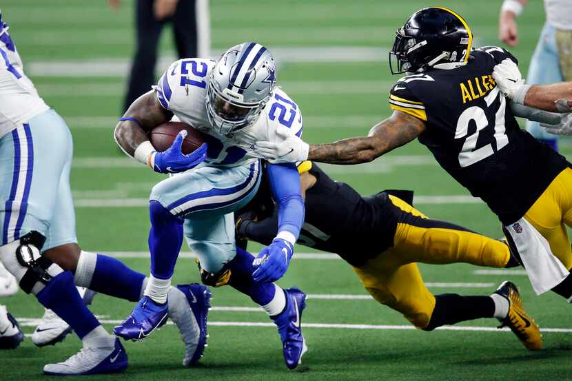 El corredor de los Dallas Cowboys, Ezekiel Elliott (21), lleva el balón entre defensivos de...