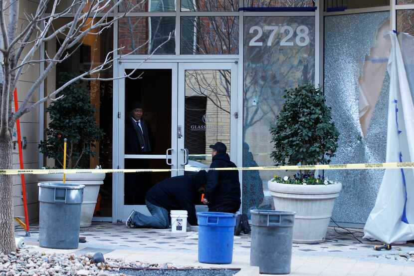 Workmen sweep up shattered glass at the Glass House by Windsor in Uptown after Dallas police...