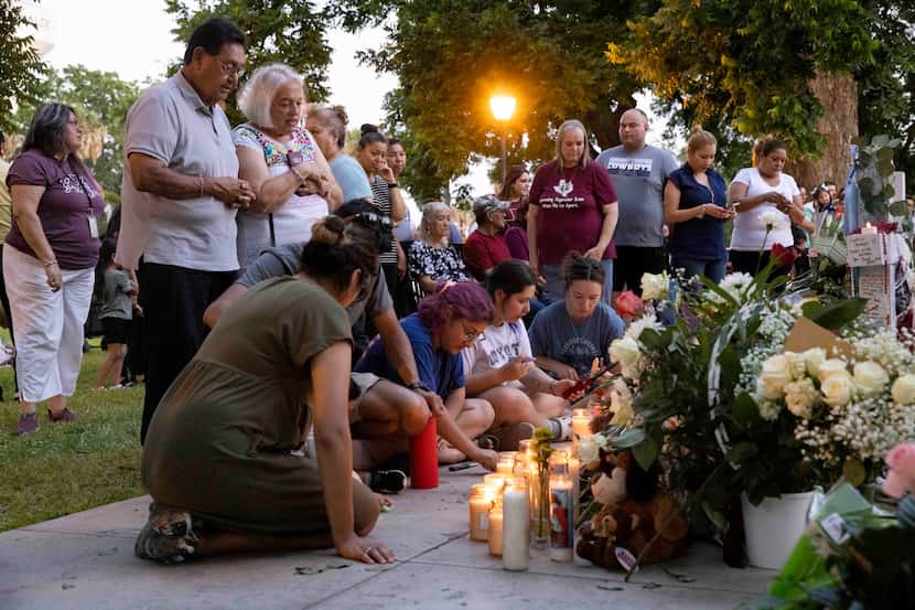 Personas se congregan alrededor del memorial en la plaza del centro de Uvalde, Texas, para...