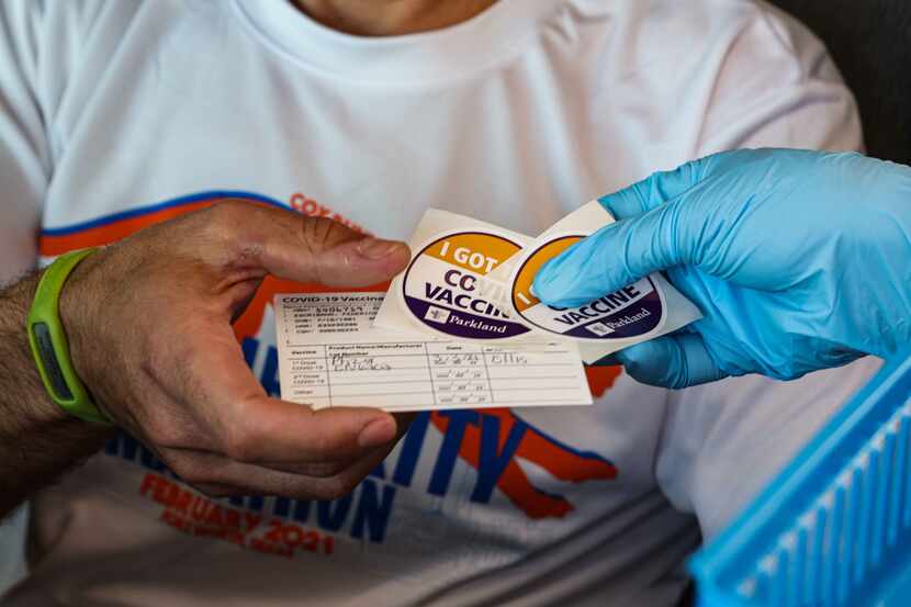 Nurse Lisa Wheeler gives back to Federico Escribano, 39, his vaccine card and some stickers...