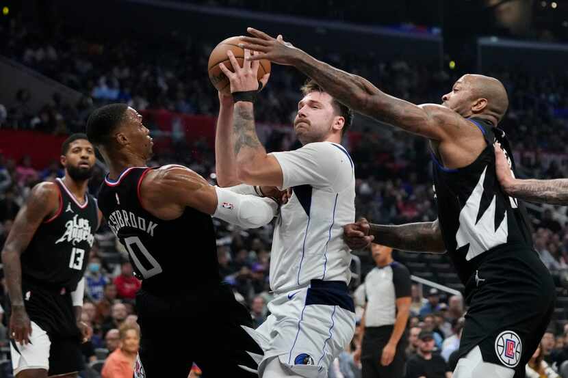 Dallas Mavericks' Luka Doncic, center, is double-teamed by Los Angeles Clippers' Russell...