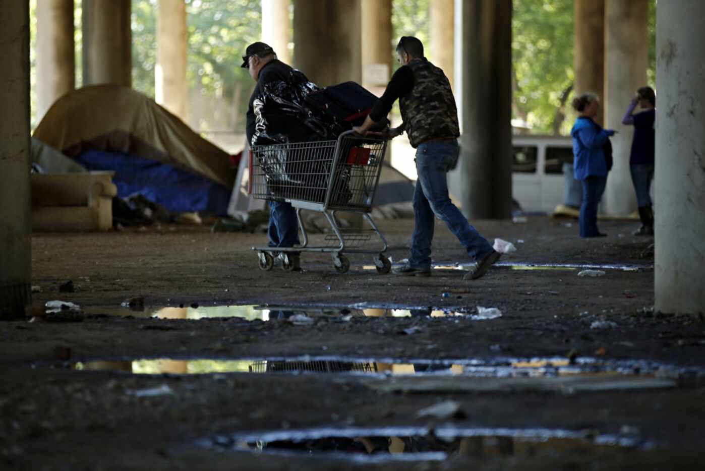 Men push a shopping cart full of belongings in Tent City Tuesday, May 3, 2016 in Dallas. The...