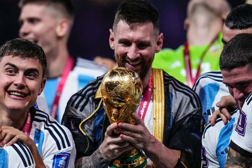 Argentina's Lionel Messi holds the trophy after winning the World Cup final soccer match...