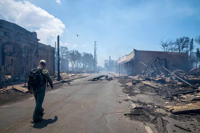 A man walks past wildfire wreckage on Wednesday, Aug. 9, 2023, in Lahaina, Hawaii. The scene...