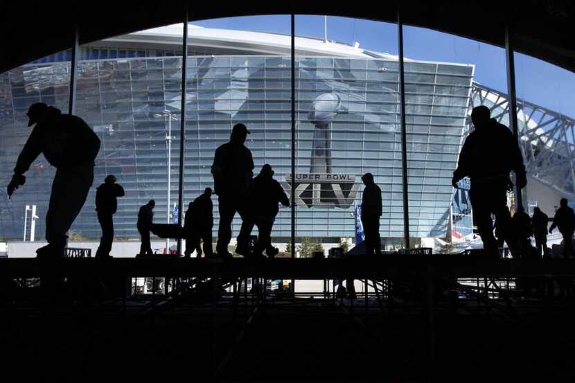 Workers disassemble the massive NFL Tailgate Party tent outside of Cowboys Stadium the day...