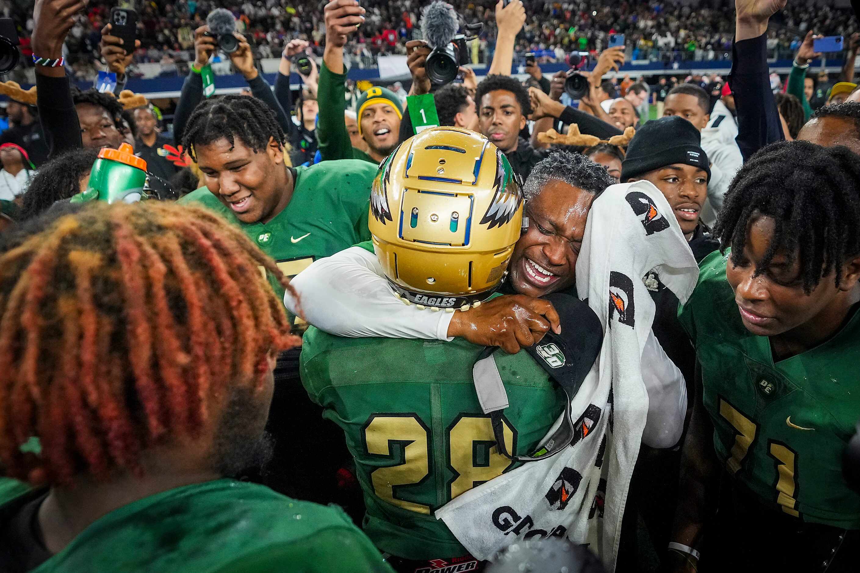 DeSoto head coach Claude Mathis hugs defensive back Caden Mathis (28) as he celebrates with...