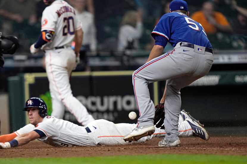 Houston Astros' Myles Straw, left, scores on a wild pitch by Texas Rangers relief pitcher...