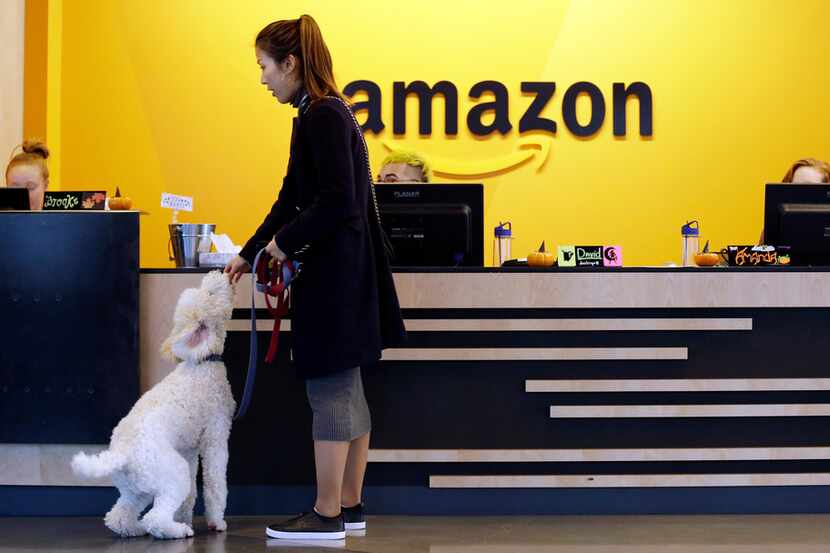 In this Wednesday, Oct. 11, 2017, photo, an Amazon employee gives her dog a biscuit as the...