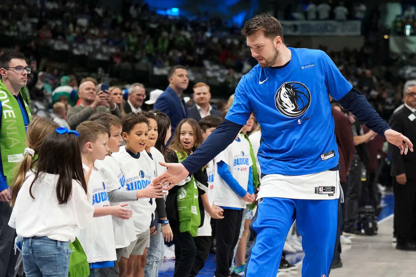 Dallas Mavericks guard Luka Doncic slaps hands with youngsters court side before the first...