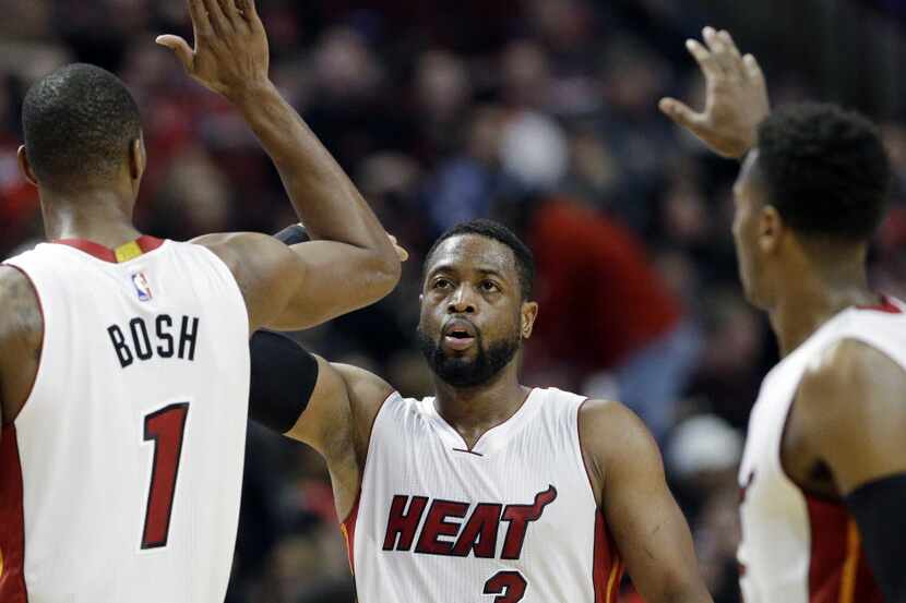 Miami Heat guard Dwyane Wade (3) celebrates with forward Chris Bosh (1) and guard Mario...