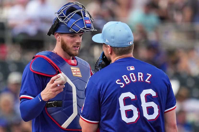 Texas Rangers pitcher Josh Sborz gets a visit from catcher Jonah Heim after giving up a home...