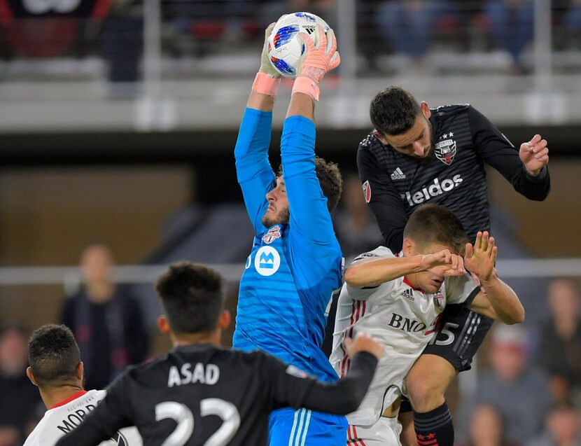 Toronto FC goalkeeper Alex Bono, center, makes a save on a kick during an MLS soccer game...