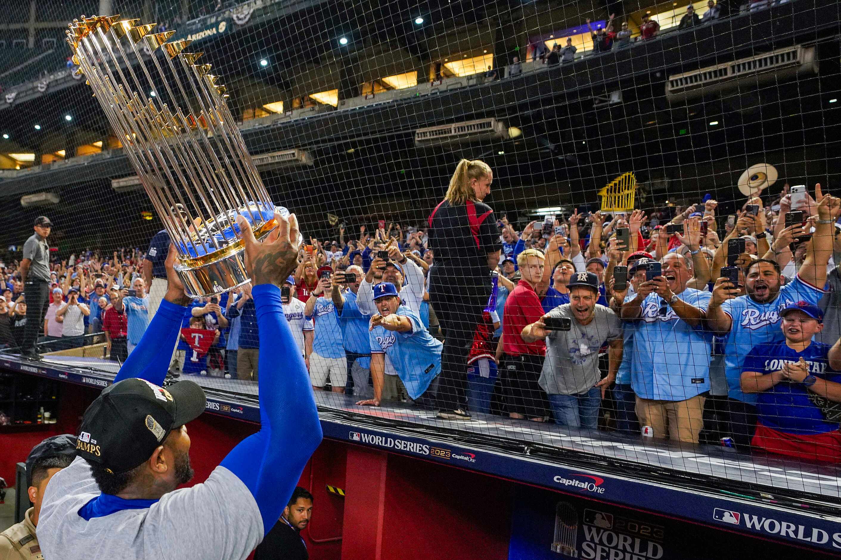 Texas Rangers relief pitcher Aroldis Chapman shows off the Commissioners Trophy to fans as...