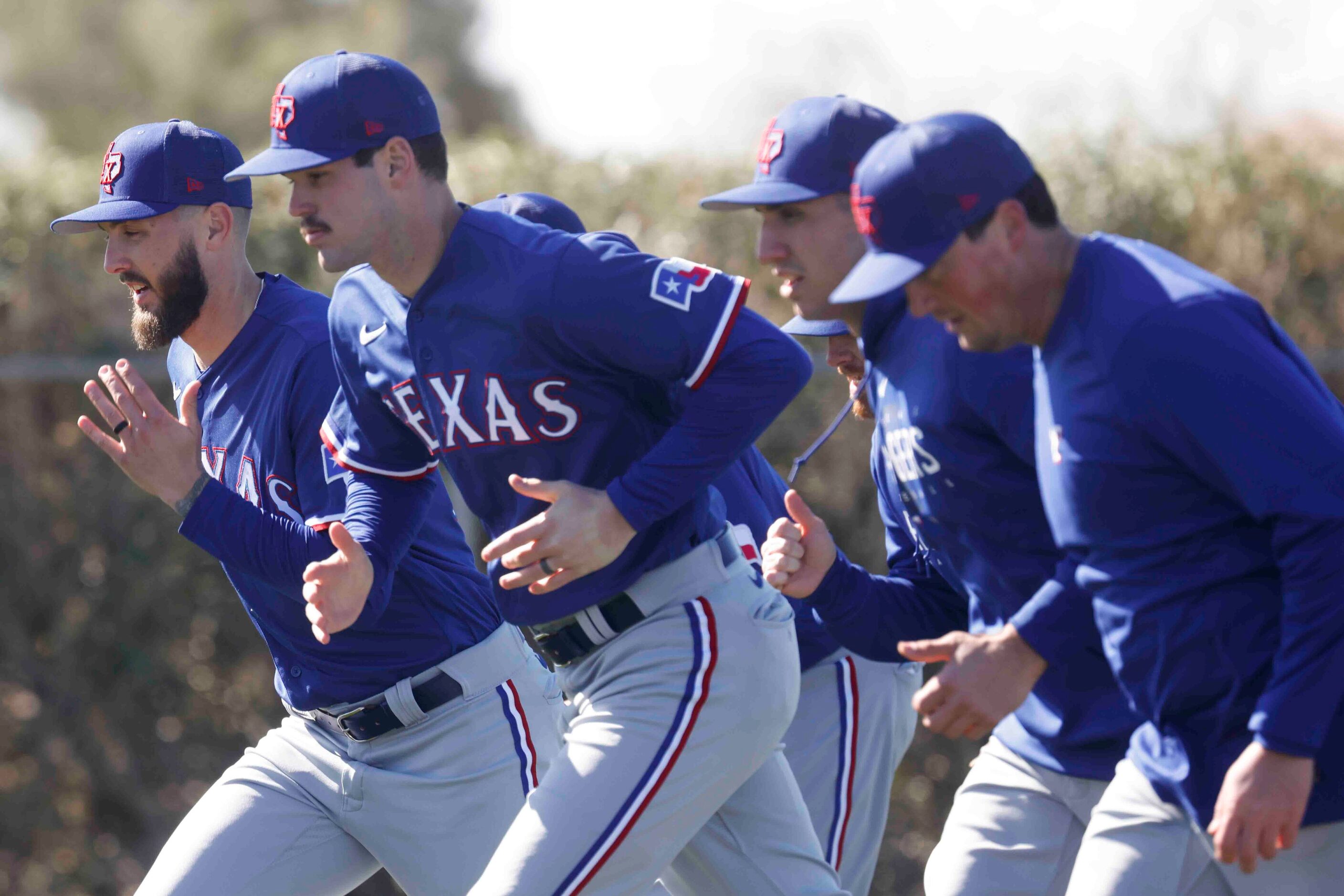 Texas Rangers players run on field during the first spring training workout for pitchers and...