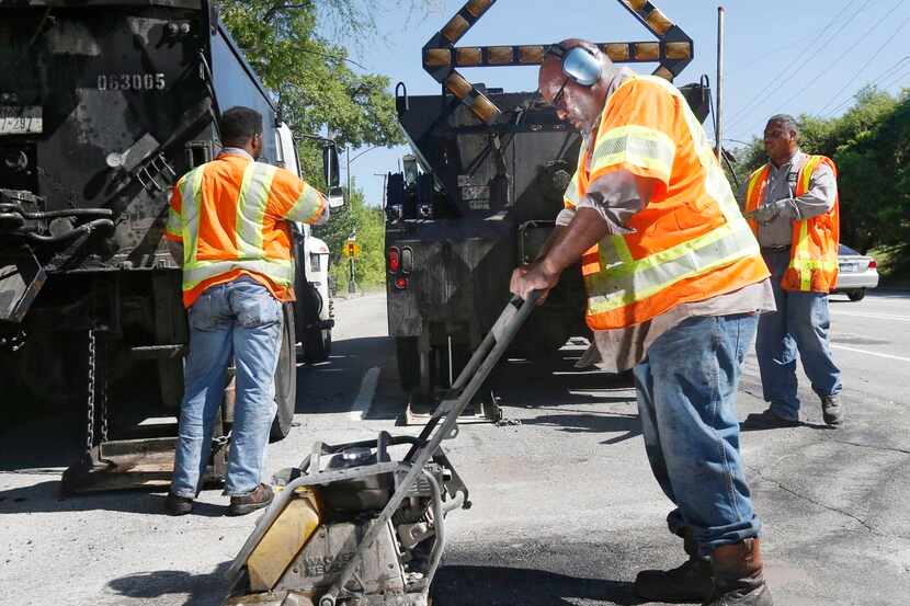 
City employee Ricky King worked to patch a pothole Wednesday on Harry Hines Boulevard. The...