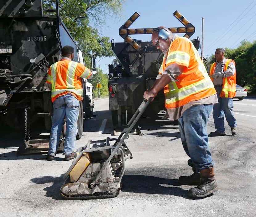 
City employee Ricky King worked to patch a pothole Wednesday on Harry Hines Boulevard. The...