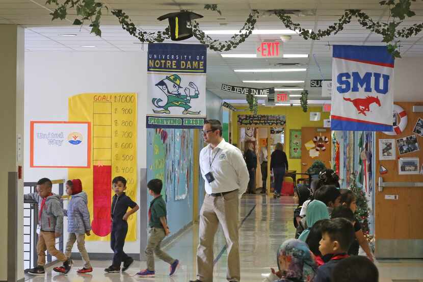 Teacher Assistant Adrian Rivera watches as students make their way through the hallways at...