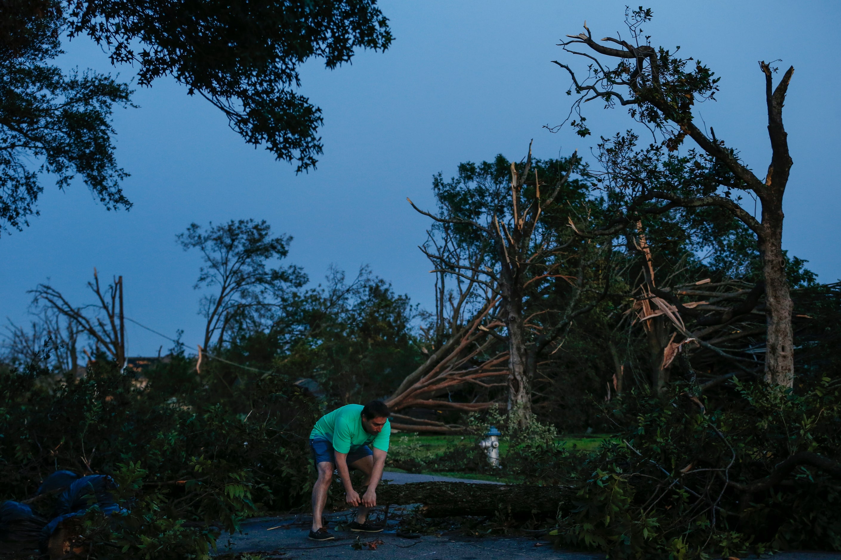 Homeowner Eric Chartan works to clear debris so he can drive his kids to school after a...