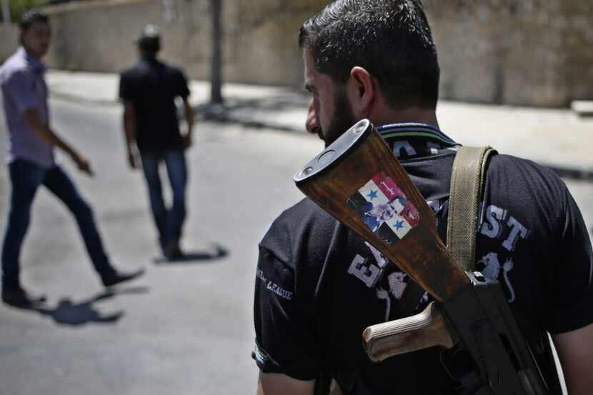 A Syrian soldier armed with an AK-47 decorated with a sticker supporting Syrian President...