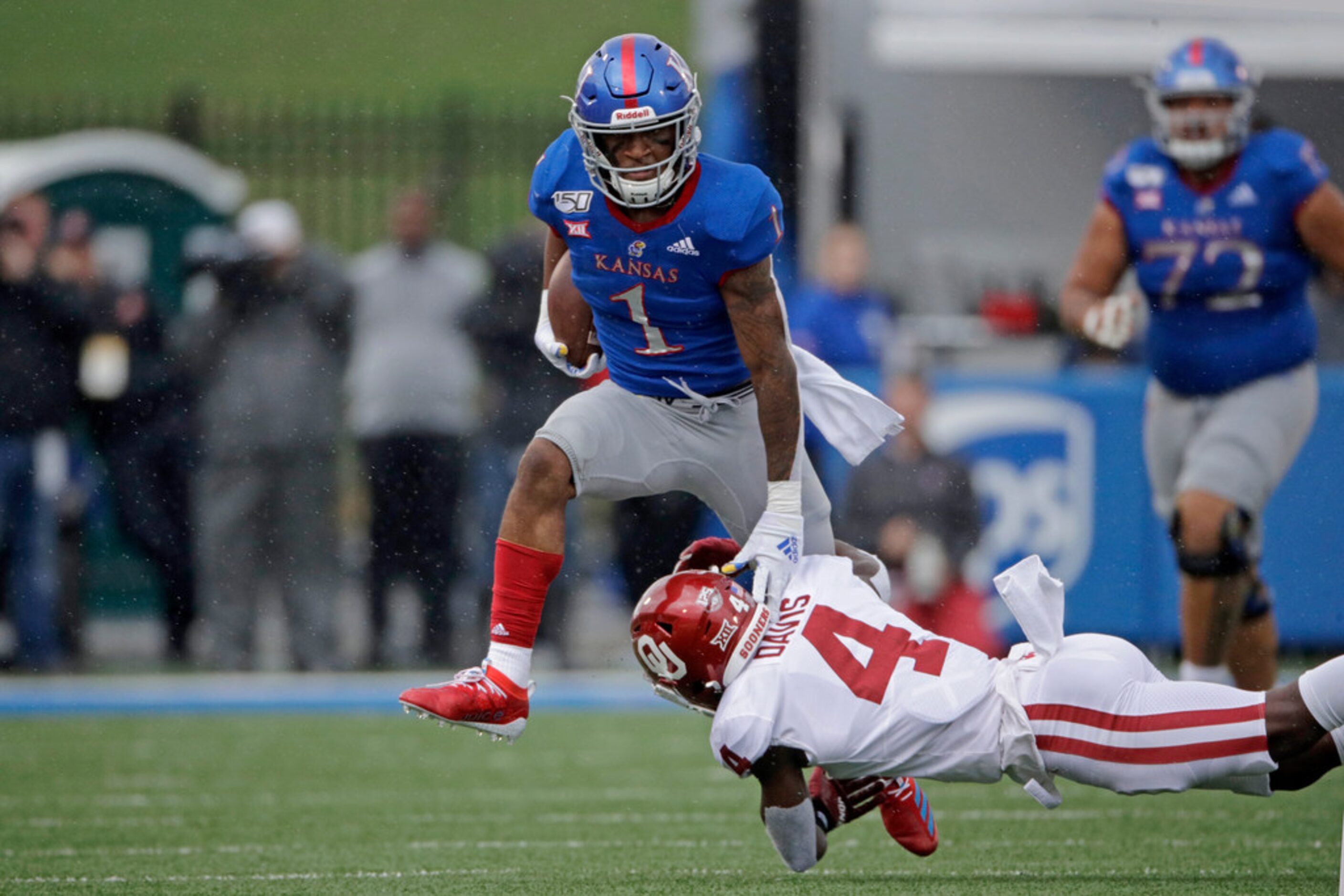 Kansas running back Pooka Williams Jr. (1) is tackled by Oklahoma cornerback Jaden Davis (4)...