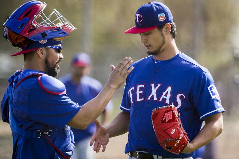 Texas Rangers pitcher Yu Darvish shakes hands with catcher Robinson Chirinos after throwing...