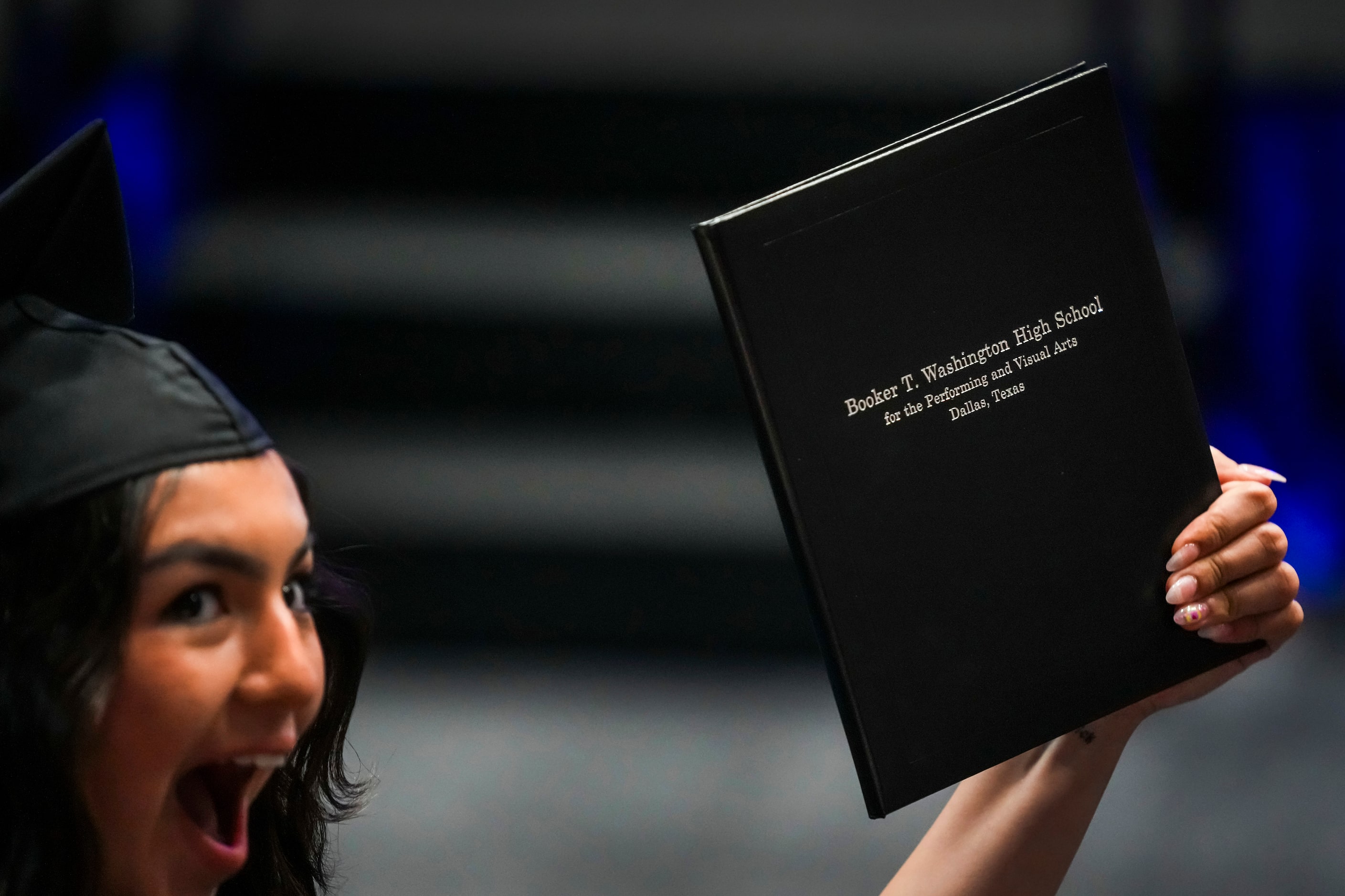 A graduate show off her diploma after crossing the stage during commencement ceremonies for...