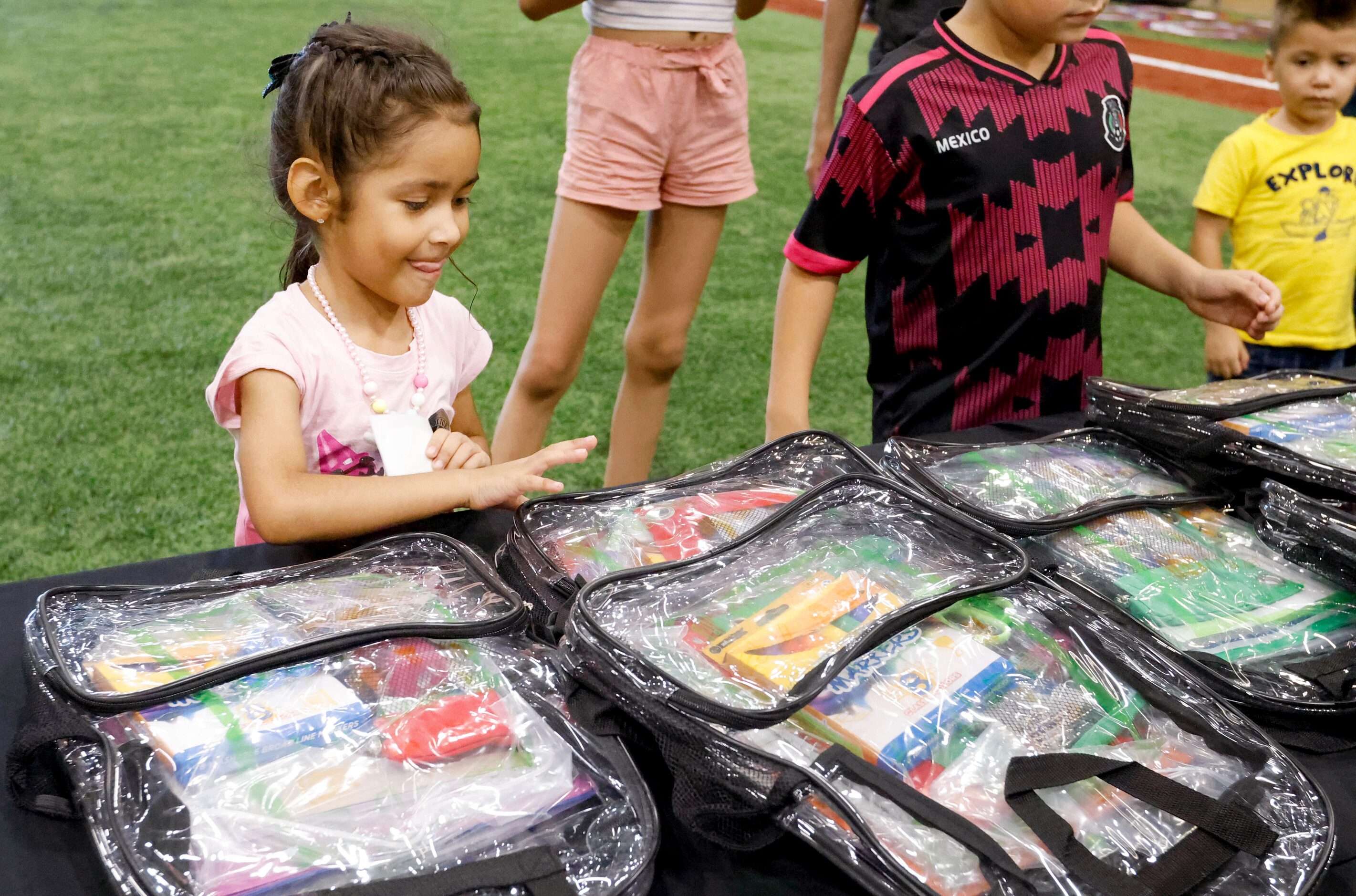 Renata Sarinana, 5, reaches for a free backpack stuffed with school supplies at the Texas...