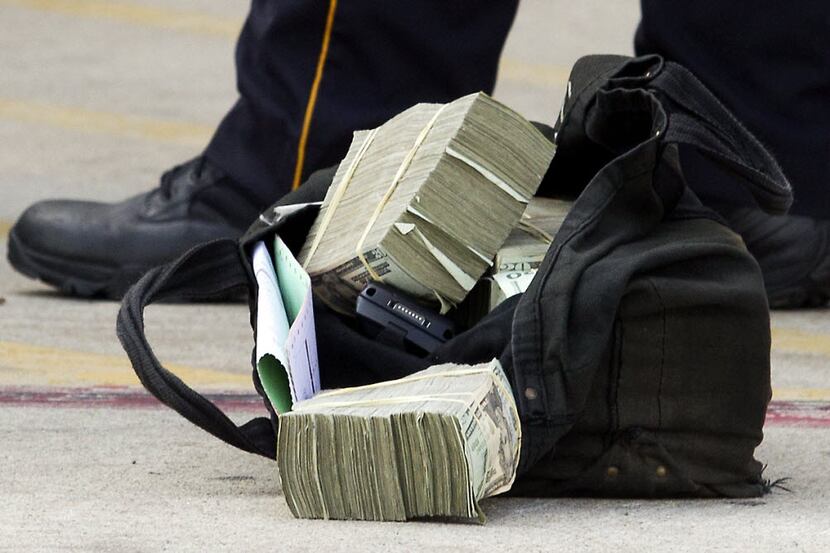 File photo - cash from an armored car heist. Grand Prairie ISD accuses its former CFO of...