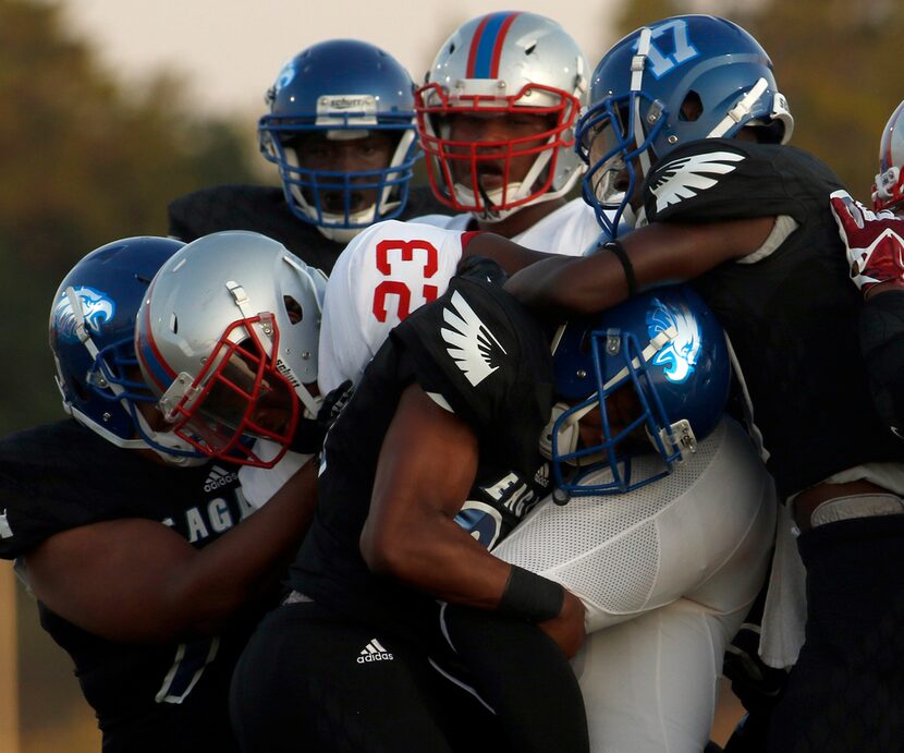 Spruce running back Jaylon Miles (23) is mobbed by a swarm of Wilmer Hutchins defenders...