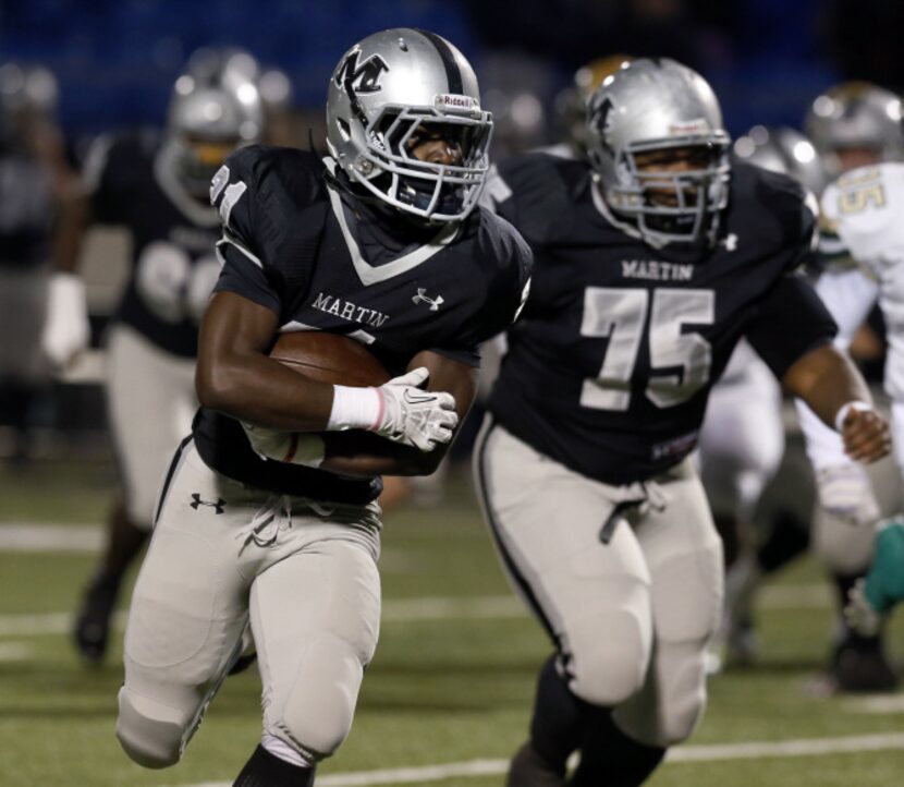 Arlington Martin High's Nic Smith (21) protects the football as he runs on a long run during...