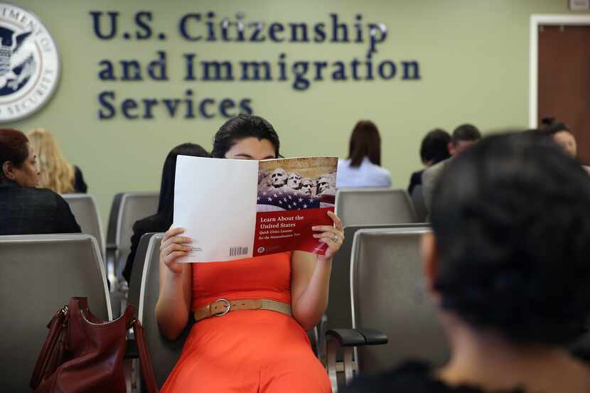 Una mujer espera en una oficina de USCIS mientras estudia su examen de ciudadanía.