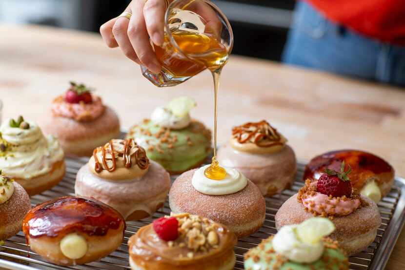 Detour Doughnuts and Coffee owner Jinny Cho tops off a cream-filled doughnut with a dollop...