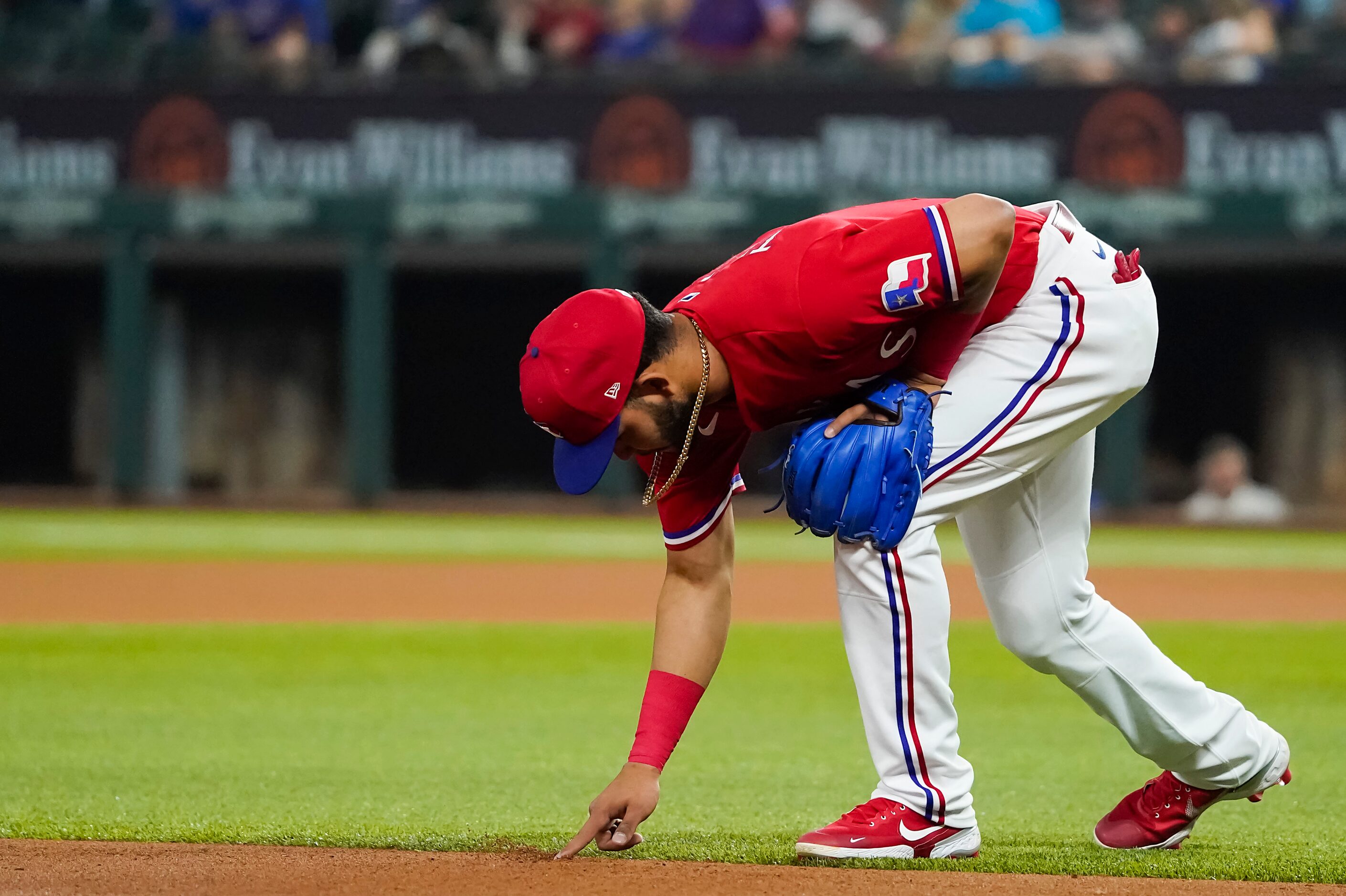 Texas Rangers third baseman Anderson Tejeda marks the infield with his finger as he takes...