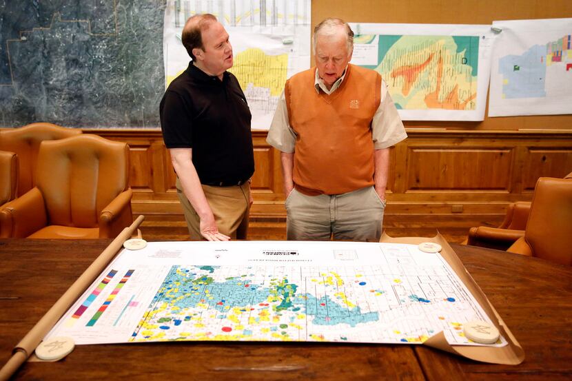 Dallas Morning News reporter Alan Peppard (left) pores over an oil and gas map with T. Boone...