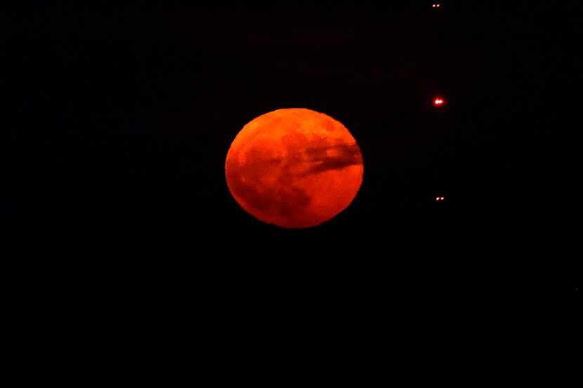 The Sturgeon Moon rises the evening of Aug. 1, 2023, with a radio tower in the foreground,...