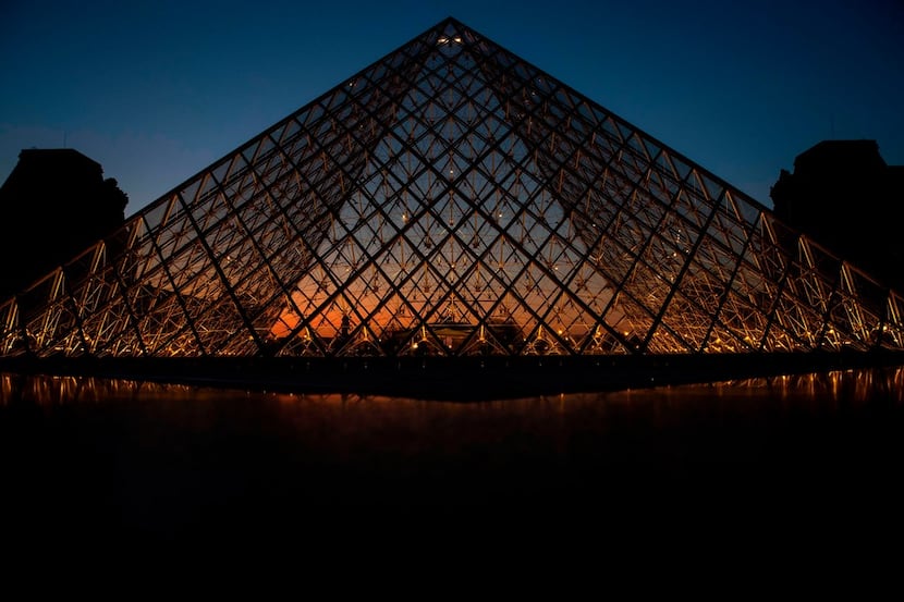 A picture taken on March 21, 2019, shows the sunset behind the Louvre Pyramid in Paris....