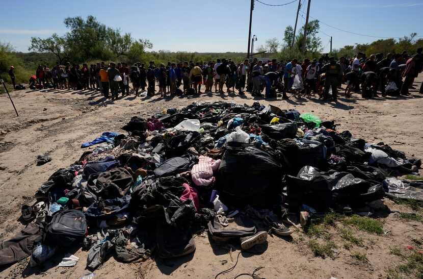 Migrants stands near a pile of discarded items as they wait to be processed by the U.S....